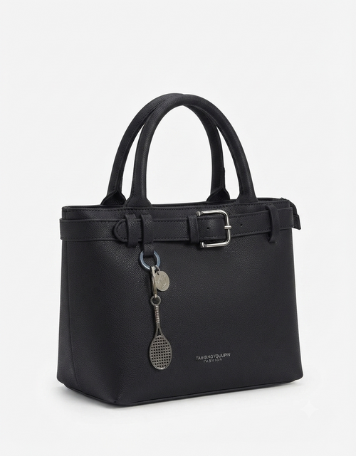 A black pebbled leather handbag with double top handles, a top zipper, a front strap detail with a silver buckle, and a hanging silver tennis racket charm, shown on a light gray background.